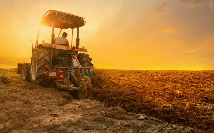 Trator preparando a terra ao pôr do sol